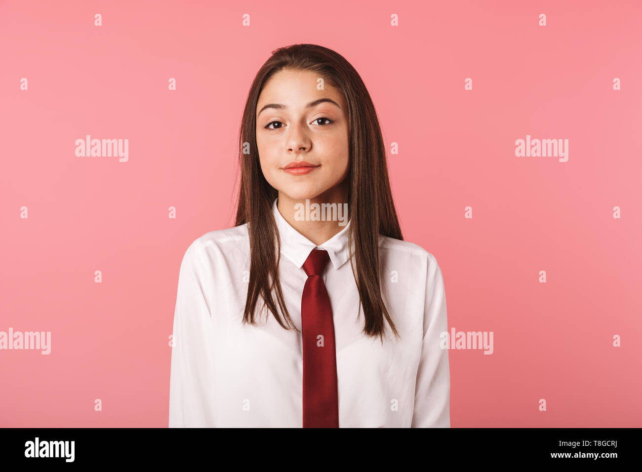 Ritratto di bella ragazza 15-16y in uniforme scolastica in piedi isolato su sfondo rosso Foto Stock