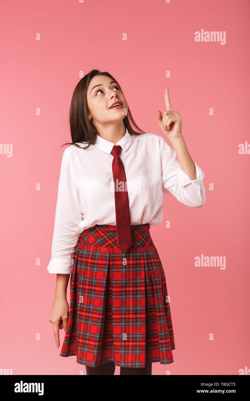 Ritratto di ragazza ottimista 15-16y in uniforme scolastica in piedi isolato su sfondo rosso Foto Stock