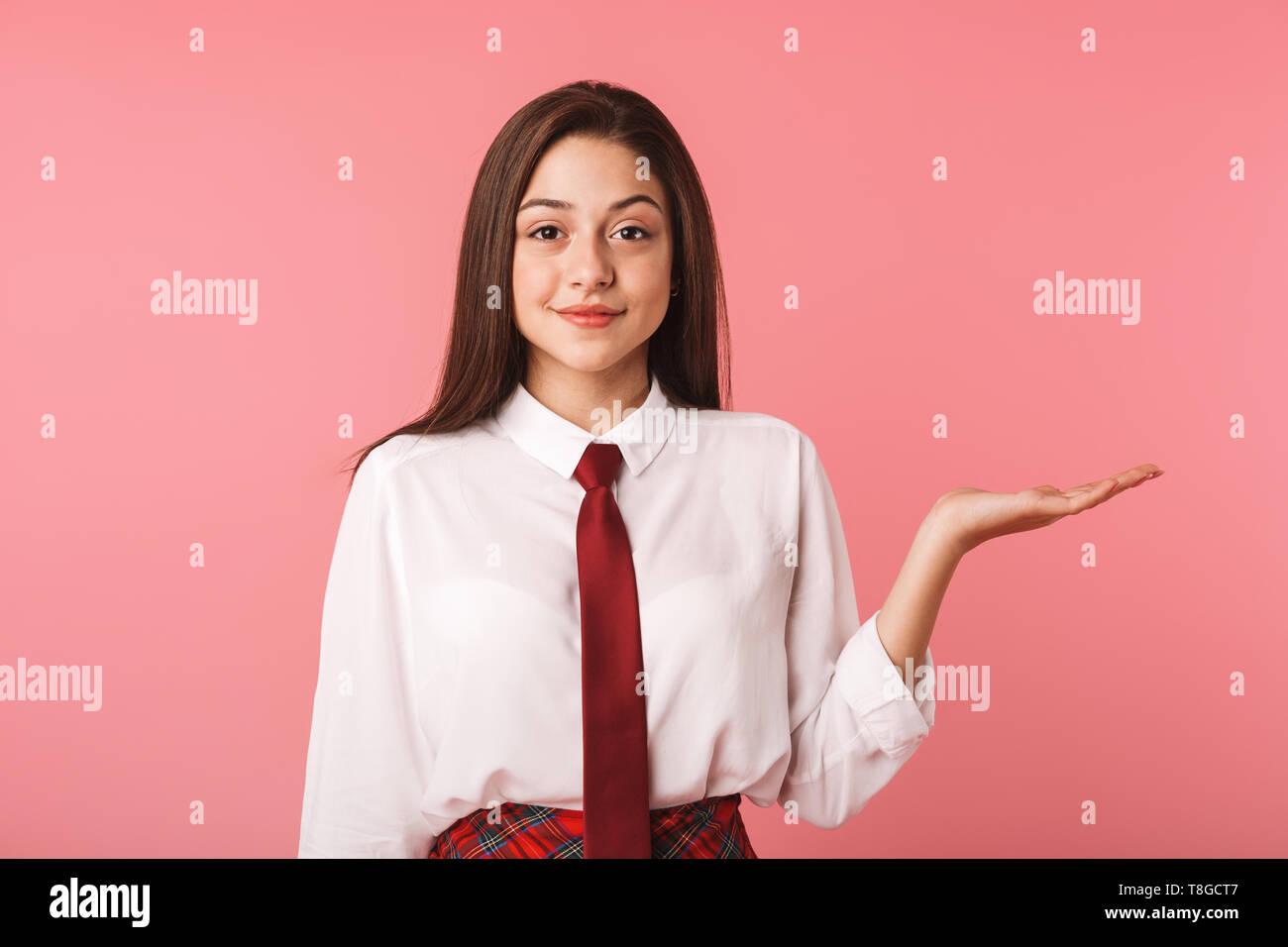 Immagine della ragazza di piacere 15-16y in uniforme scolastica in piedi isolato su sfondo rosso Foto Stock