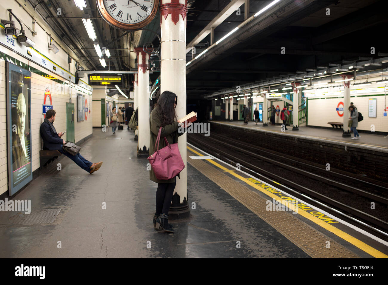 La metropolitana di Londra. Stazione di Tempio. La donna la lettura in attesa di un treno. Foto Stock