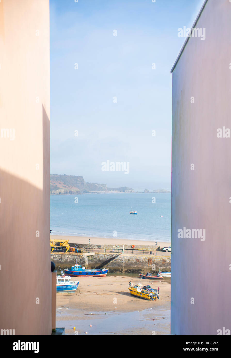 Una vista del mare tra due edifici in Tenby, nel Galles del Sud, in una giornata di sole. Foto Stock