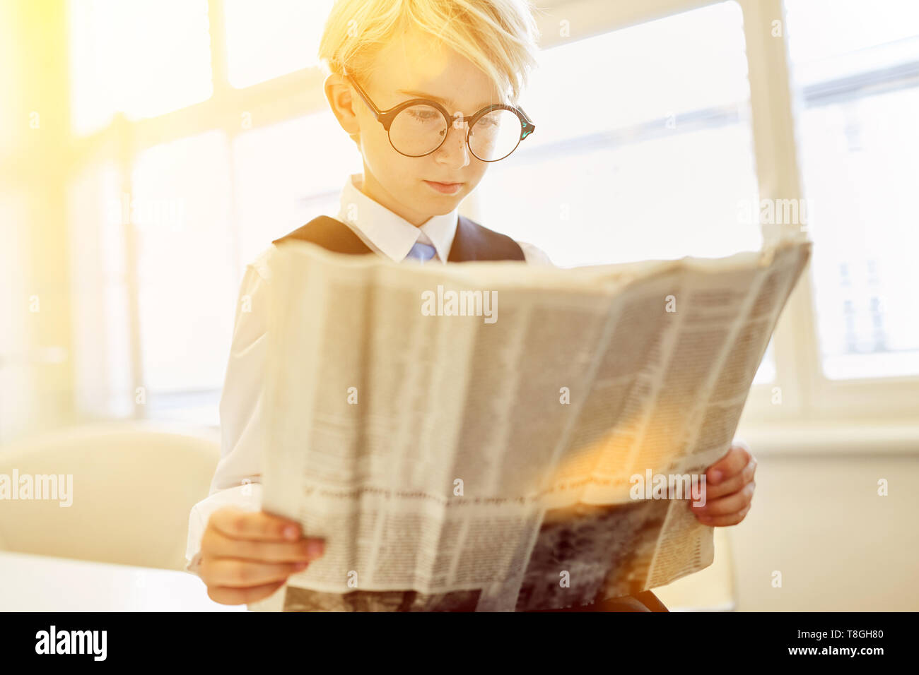 Business kid leggendo il giornale come imprenditore in ufficio Foto Stock