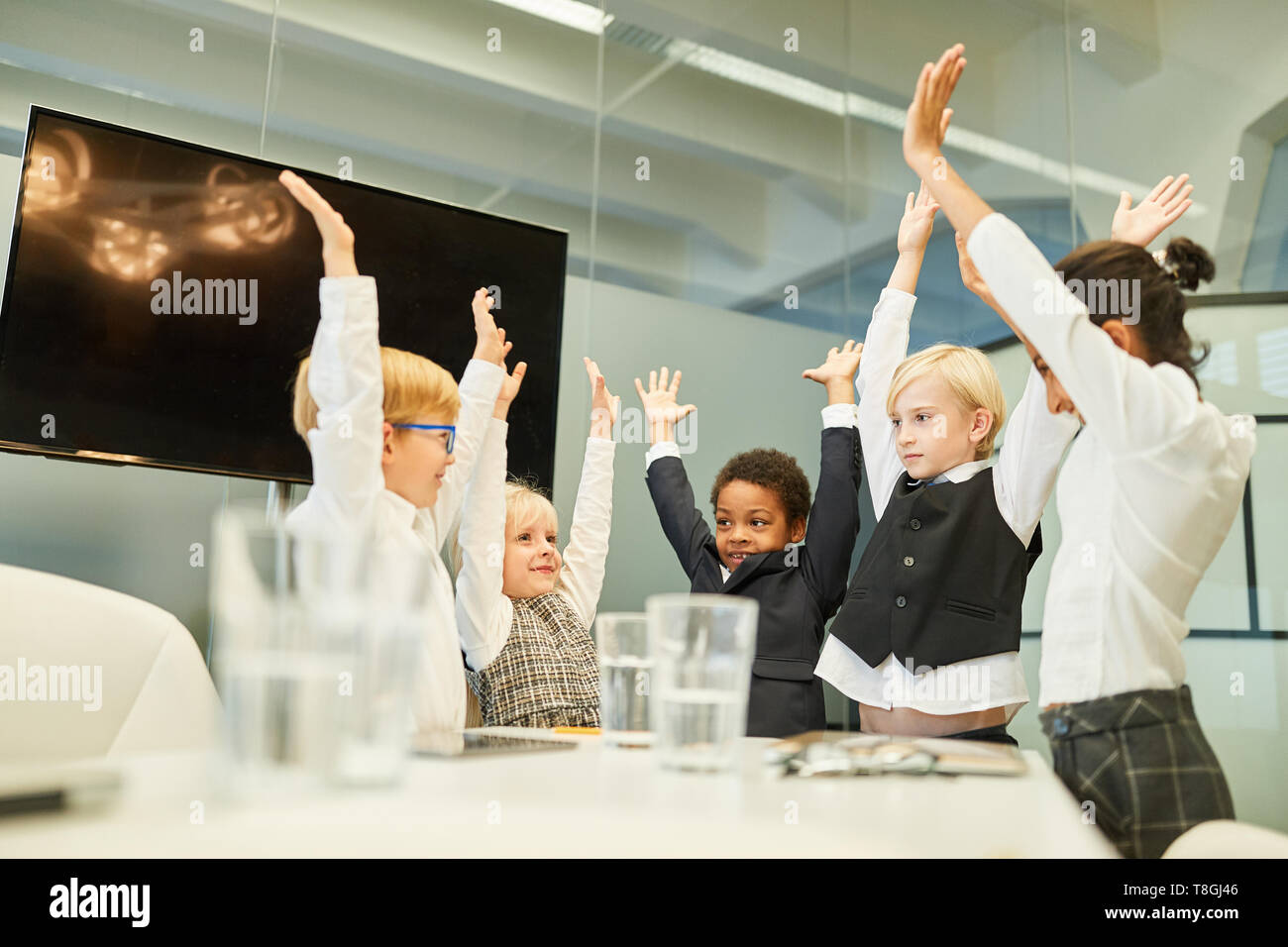 I bambini come la gente di affari nel team building workshop tendere le loro mani sopra le loro teste Foto Stock