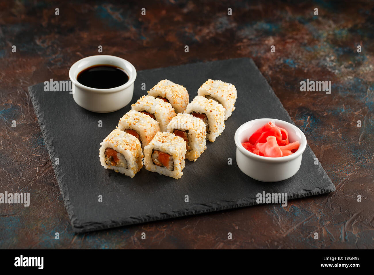 I sushi giapponesi Le bobine servita su pietra ardesia su sfondo scuro. Sushi rotoli maki, zenzero sott'aceto e salsa di soia. Sfondo di sushi. Asian o giapponese fo Foto Stock