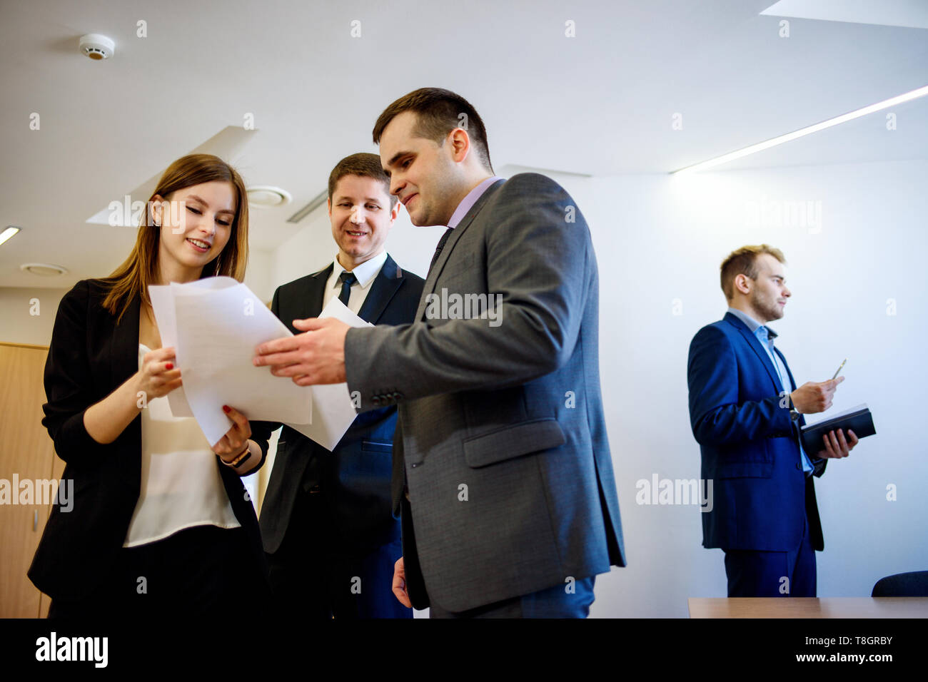 Imprenditori con il collega di sesso femminile si erge con documenti in ufficio. Foto Stock