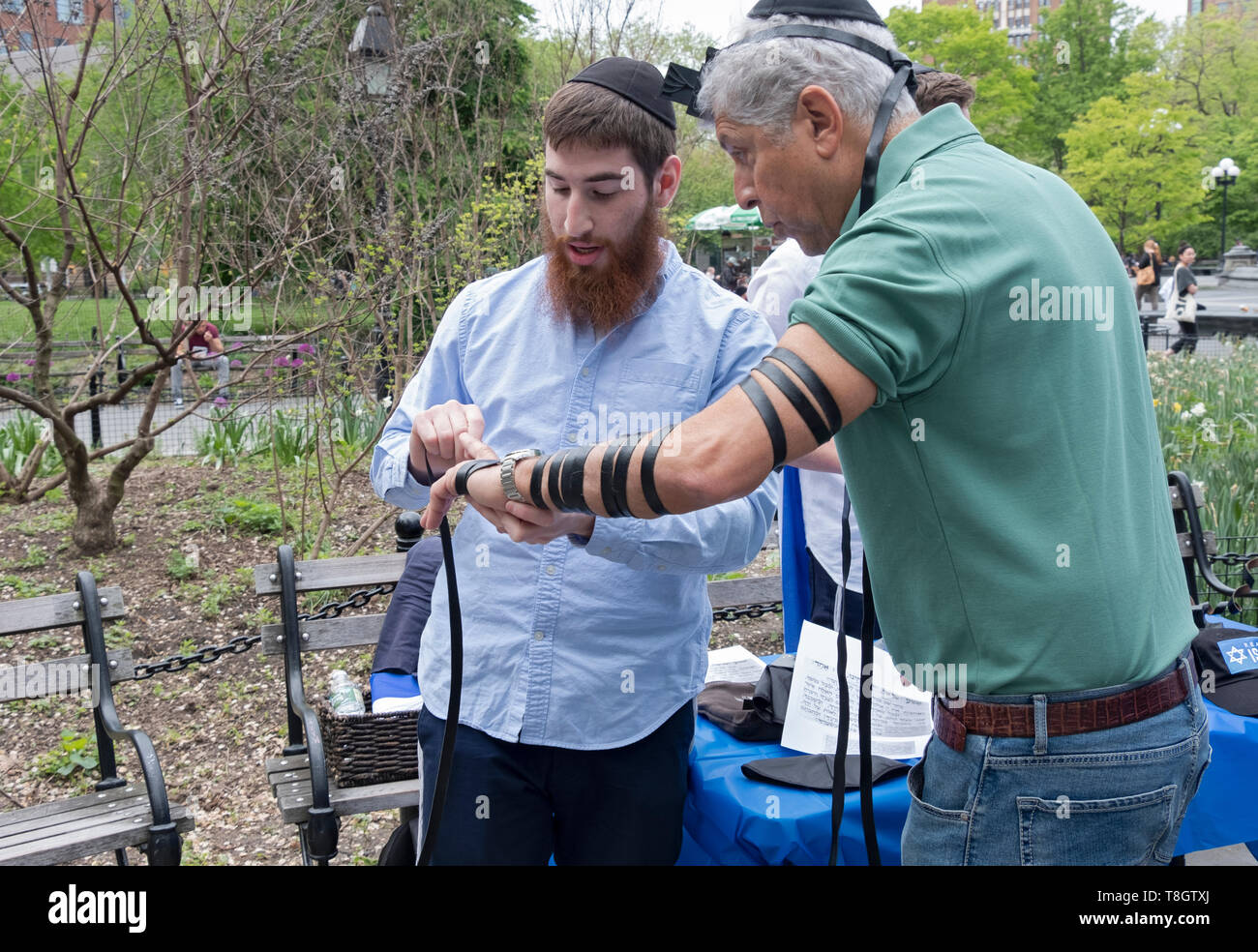 Un rabbino Chabad aiuta un uomo più anziano messo sul tefillin in Israele il giorno di indipendenza in festa a Washington Square Park, in New York City. Foto Stock