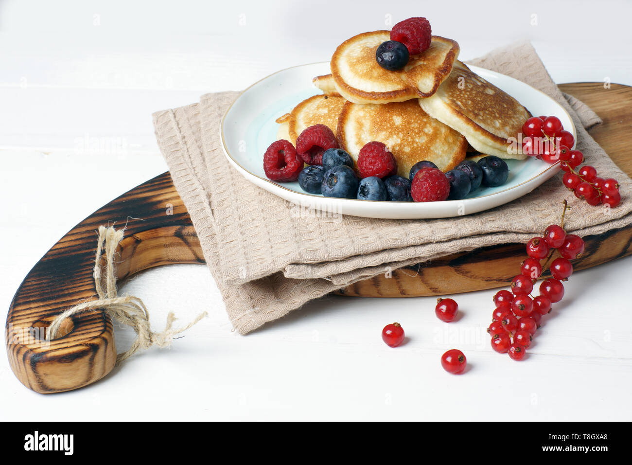 Composizione della luce con pancake per colazione con frutti di bosco freschi di ribes, mirtillo e lampone Foto Stock