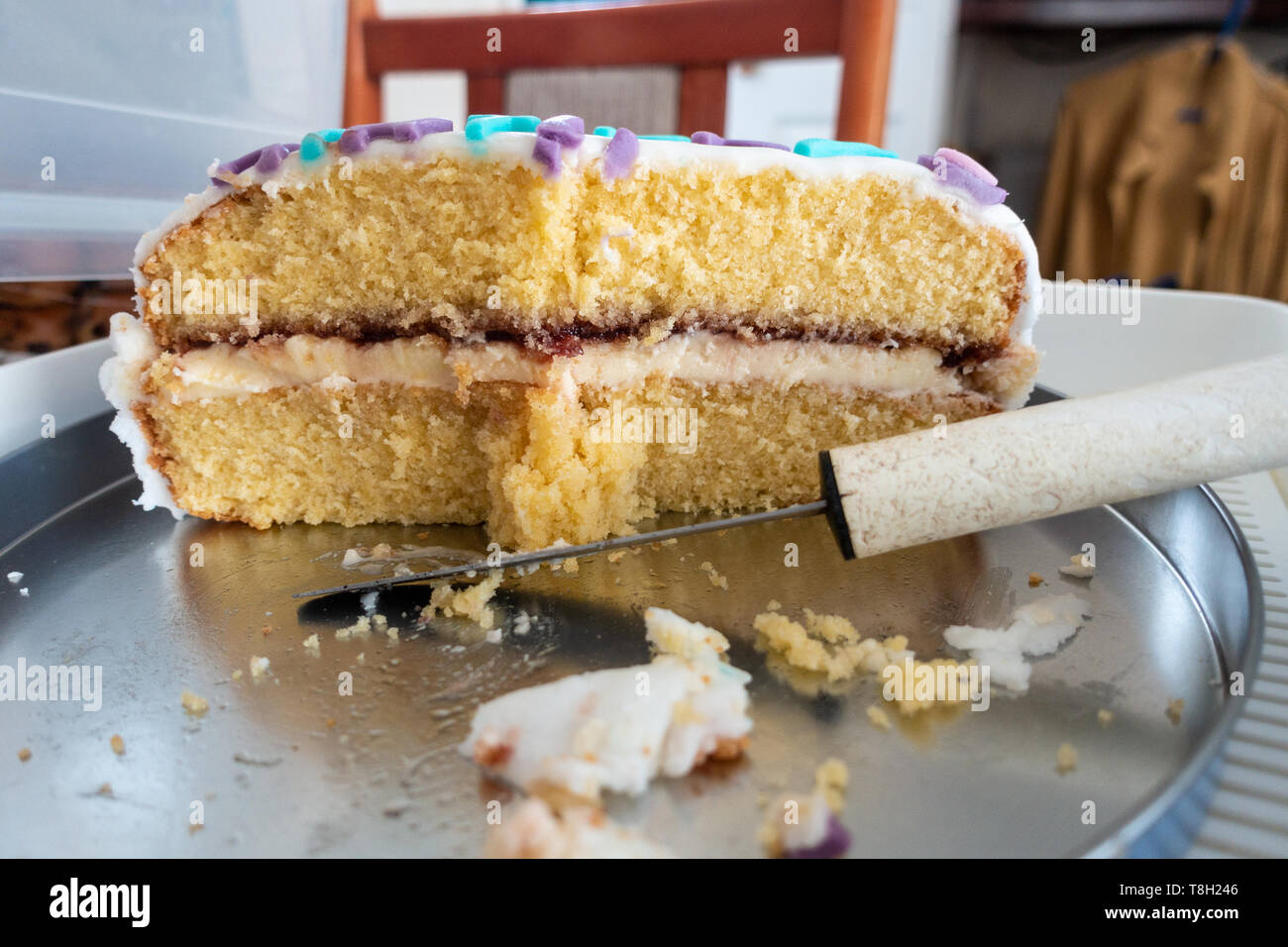 Una metà mangiato torta di compleanno su una tabella con un coltello. Foto Stock