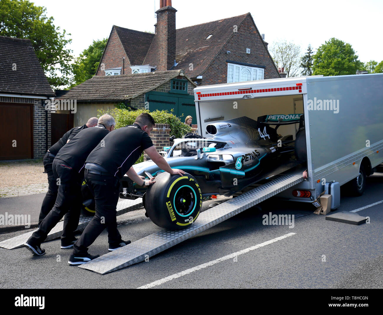 Membri della Mercedes Formula One team a fornire una replica di Lewis Hamilton della vettura di Formula 1 per la casa di cinque anni di Harry Shaw in Redhill Surrey, che è stato diagnosticato con una rara forma di cancro osseo. Foto Stock