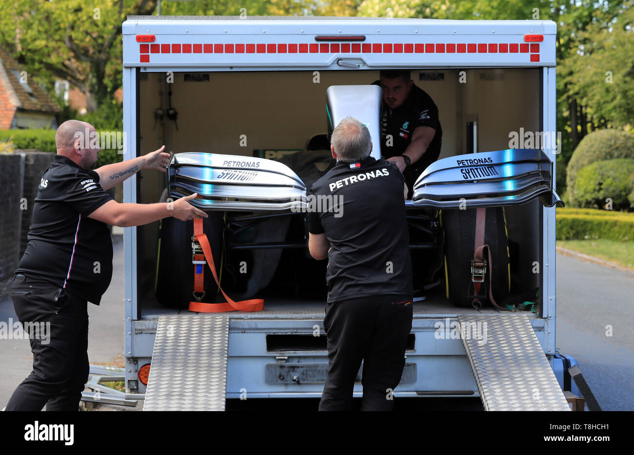 Membri della Mercedes Formula One team a fornire una replica di Lewis Hamilton della vettura di Formula 1 per la casa di cinque anni di Harry Shaw in Redhill Surrey, che è stato diagnosticato con una rara forma di cancro osseo. Foto Stock