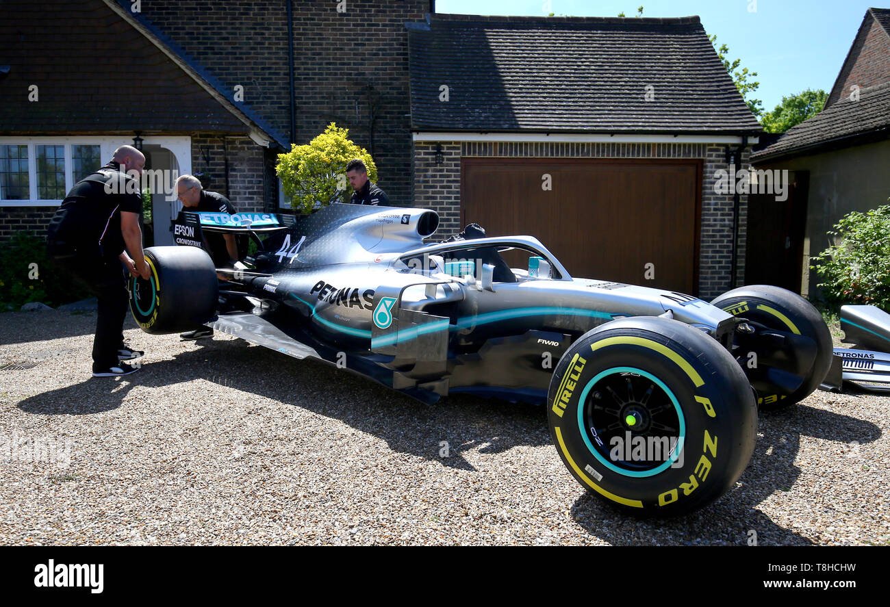 Membri della Mercedes Formula One team a fornire una replica di Lewis Hamilton della vettura di Formula 1 per la casa di cinque anni di Harry Shaw in Redhill Surrey, che è stato diagnosticato con una rara forma di cancro osseo. Foto Stock