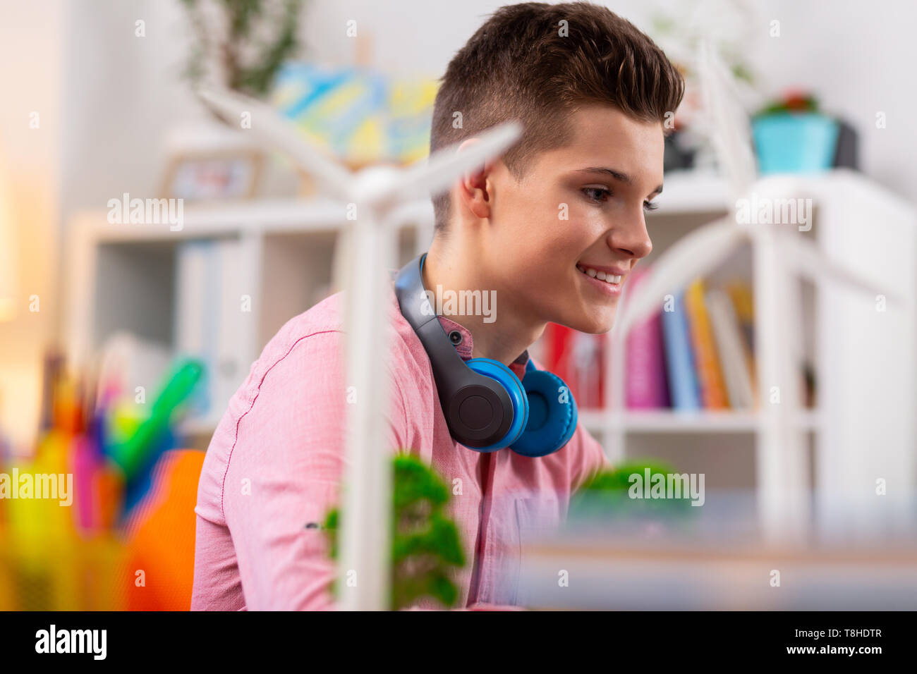 Adolescente che indossa gli auricolari blu sul collo lo studio dell'ecologia Foto Stock