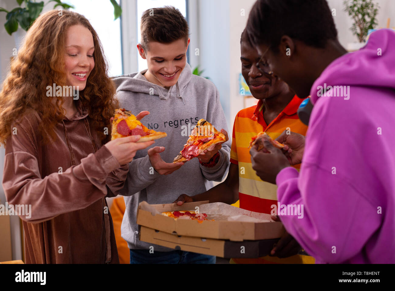 Quattro adolescenti mangiare deliziosa pizza dopo lo studio Foto Stock