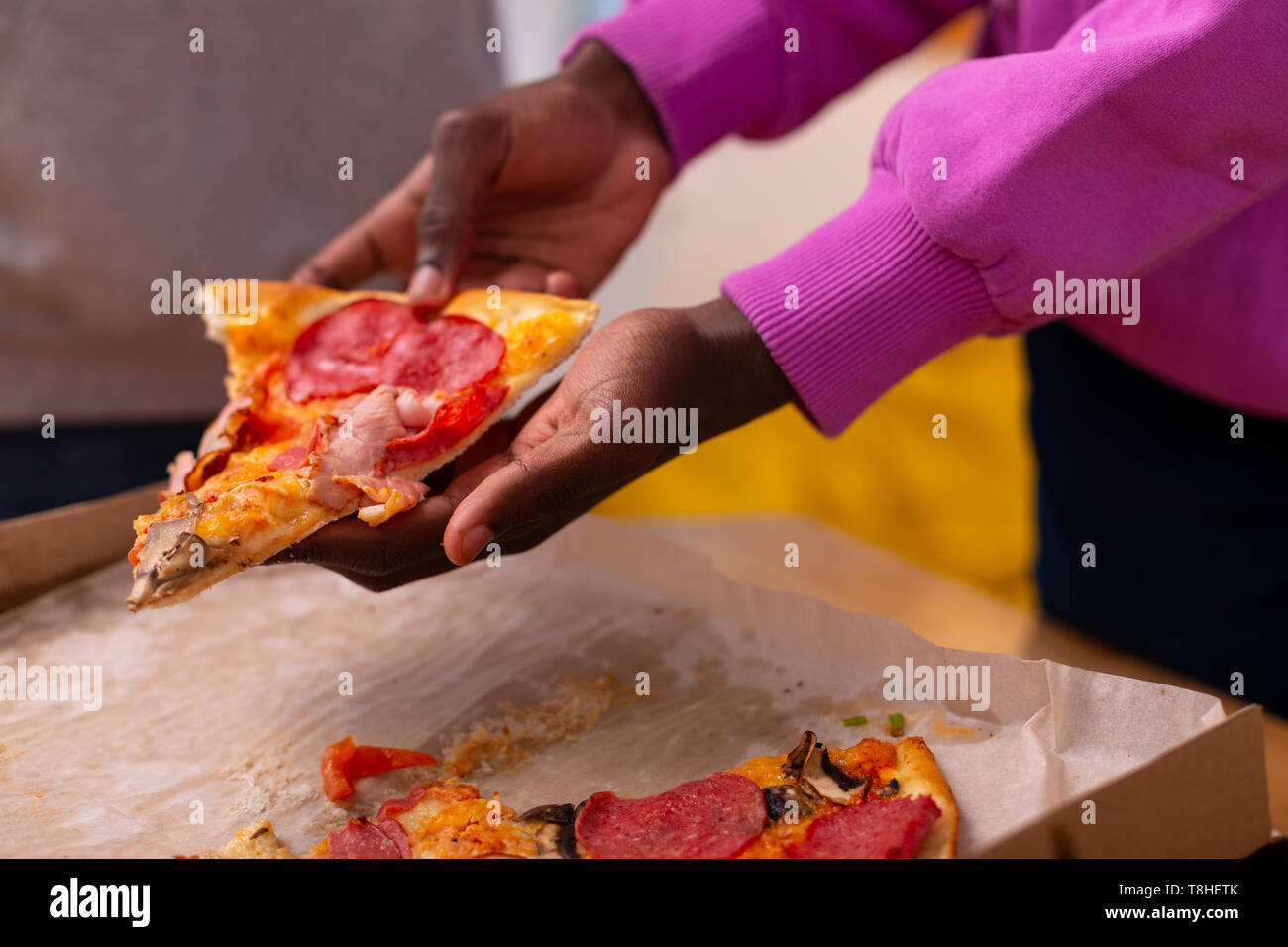 Adolescente in viola felpa tenendo la pizza con salame Foto Stock
