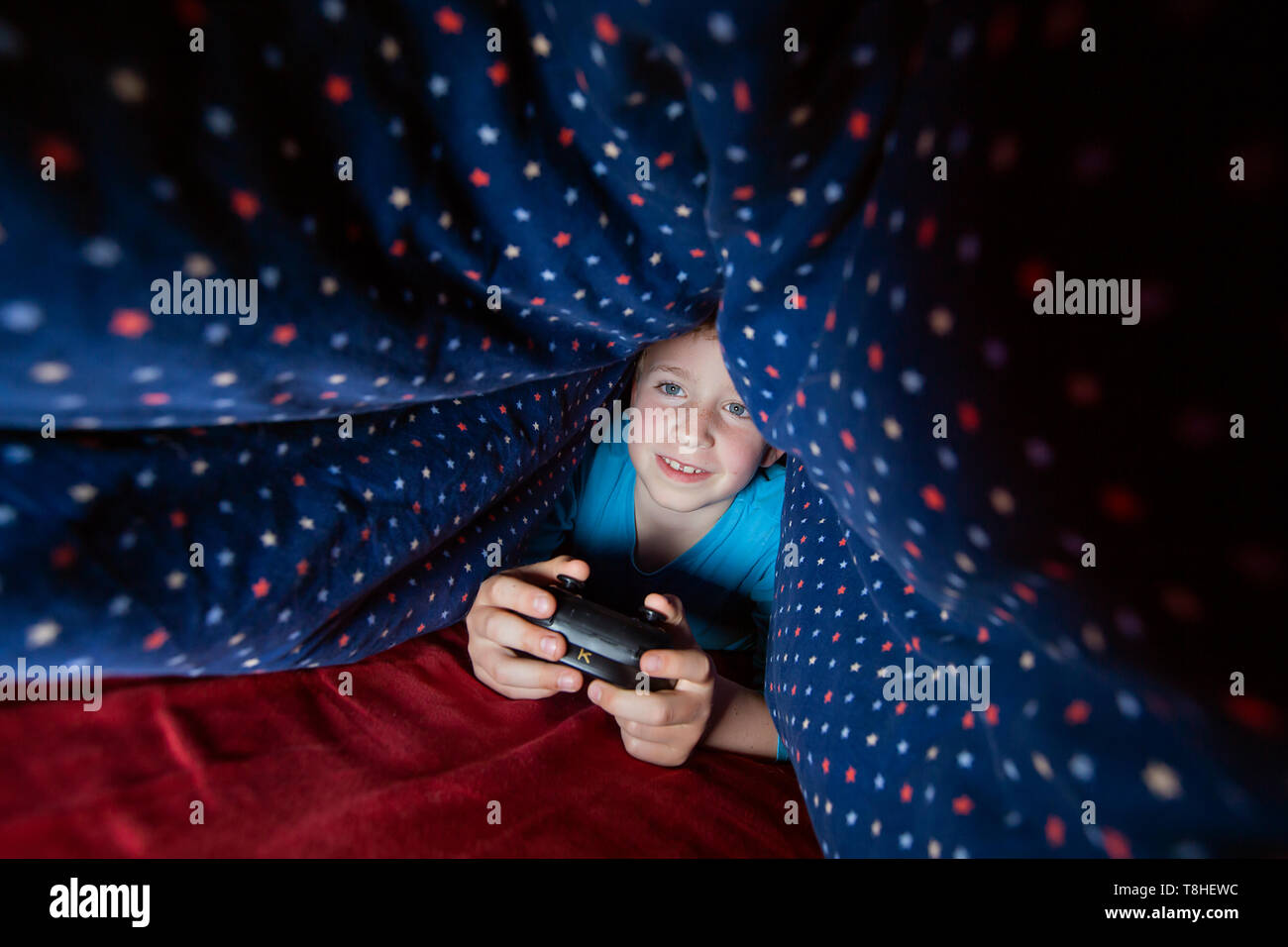 Il ragazzo, 8 anni, sectretly giocando a un gioco per computer a letto Foto Stock