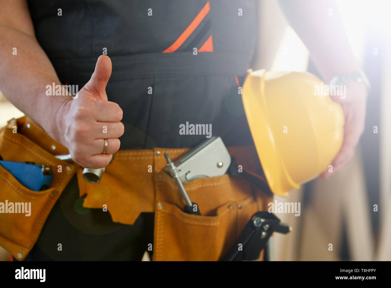 Mano del lavoratore nel casco giallo visualizza confermare Foto Stock