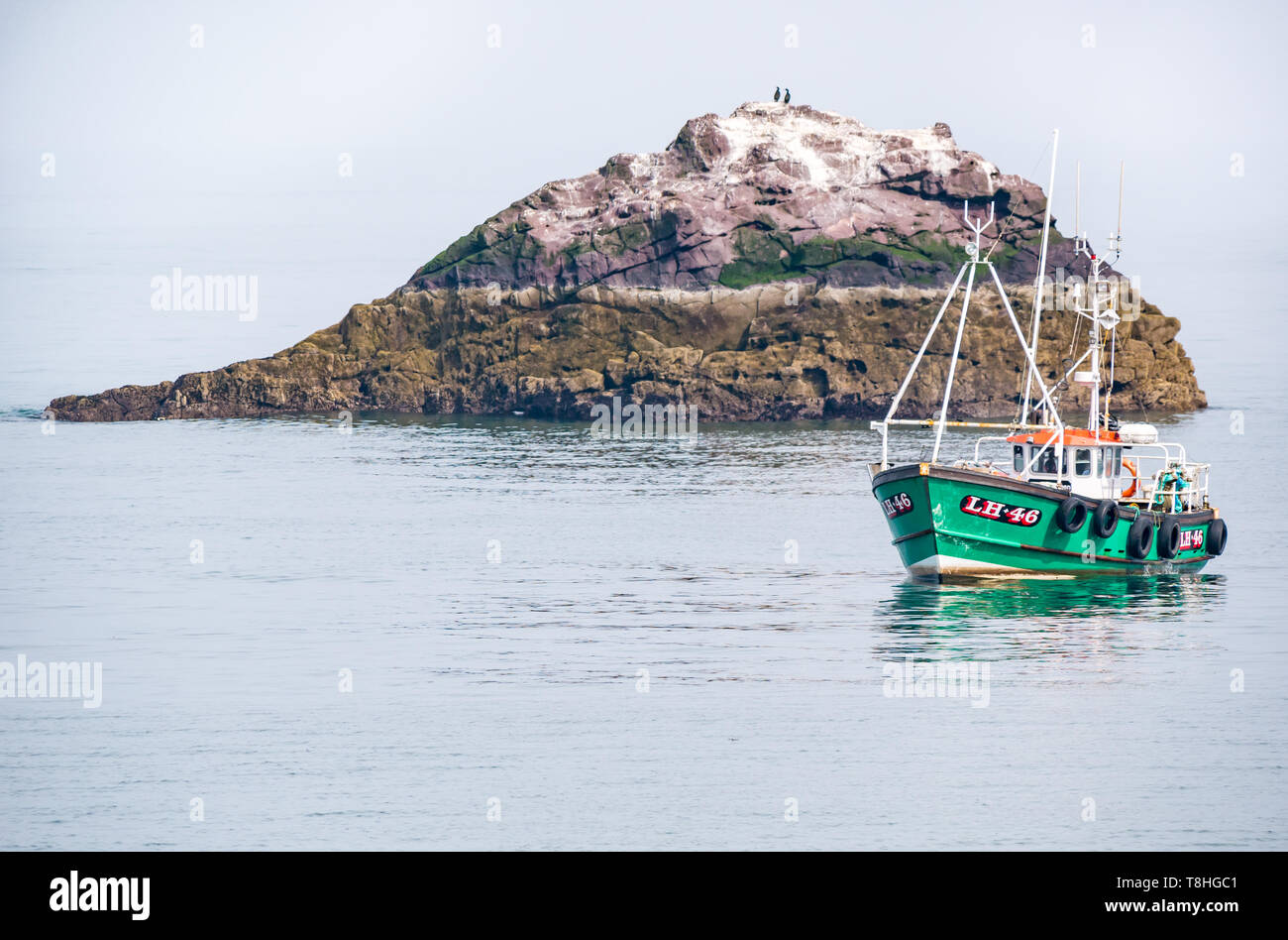 Dunbar barca da pesca in mare calmo accanto alla piccola isola rocciosa con uccelli marini, Firth of Forth, East Lothian, Scozia, Regno Unito Foto Stock