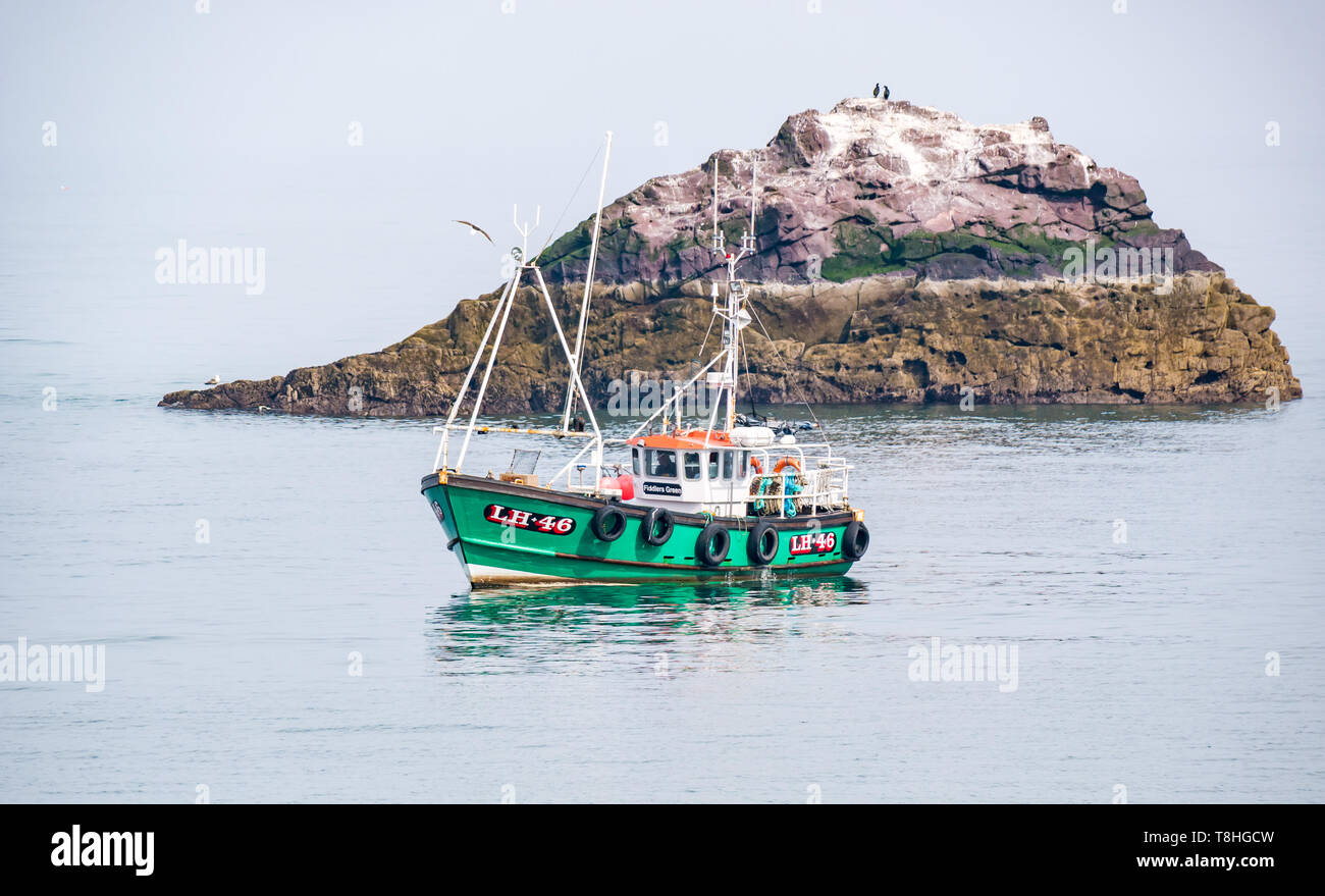 Dunbar barca da pesca in mare calmo accanto alla piccola isola rocciosa con uccelli marini, Firth of Forth, East Lothian, Scozia, Regno Unito Foto Stock