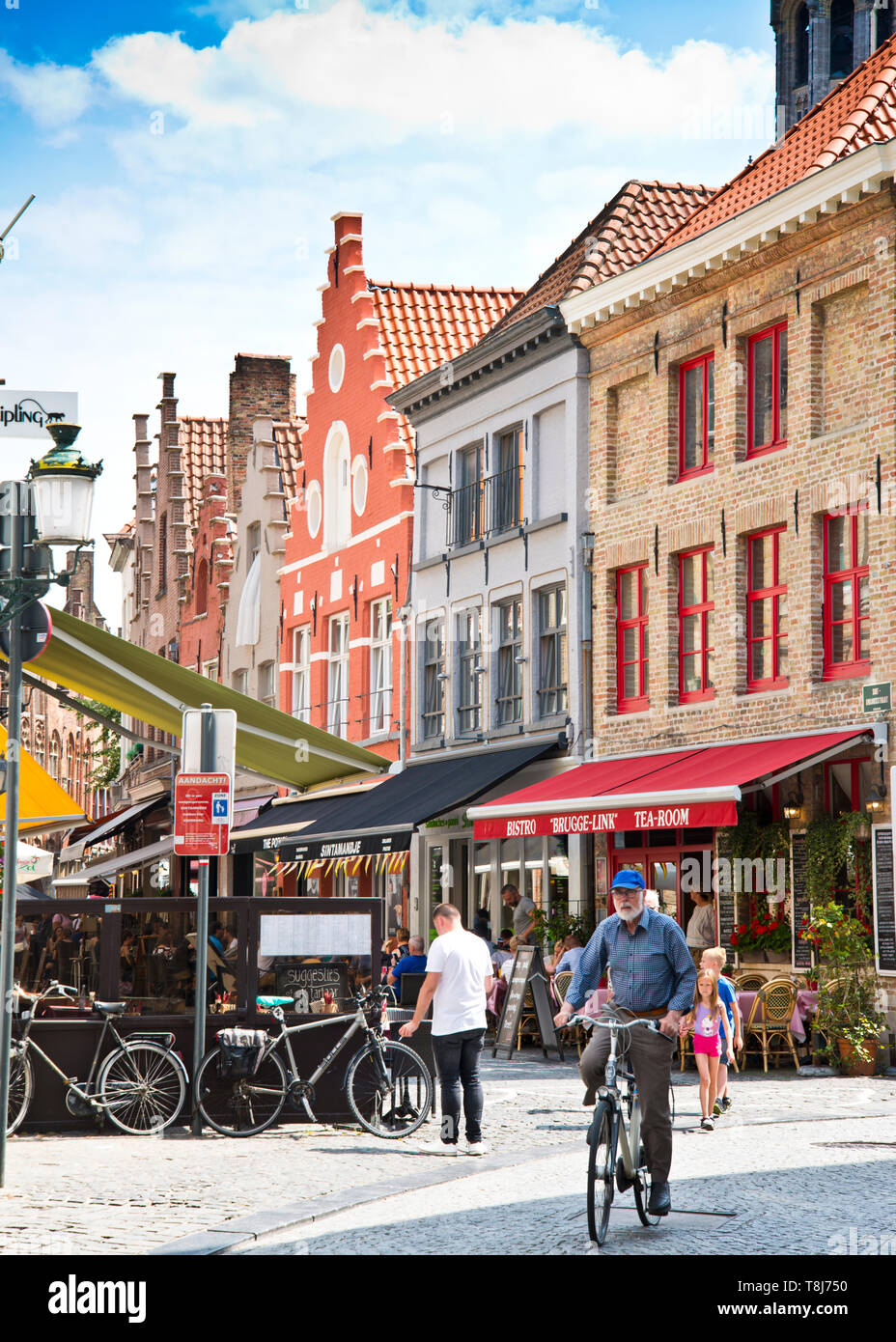 Piccola strada secondaria, nel centro storico di bruges, gente a piedi, anziano uomo in bicicletta godendo di un lento giro attraverso strade acciottolate, brugge, Belgio. Foto Stock