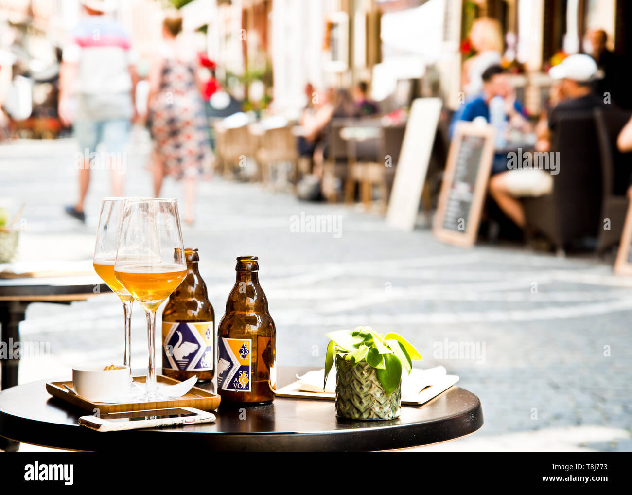 cibo, antipasti, bevande alcoliche, birra in bicchieri su un piccolo tavolo rotondo all'esterno, gruppi di persone in background all'aperto, seduti in un caffè di fronte, Foto Stock