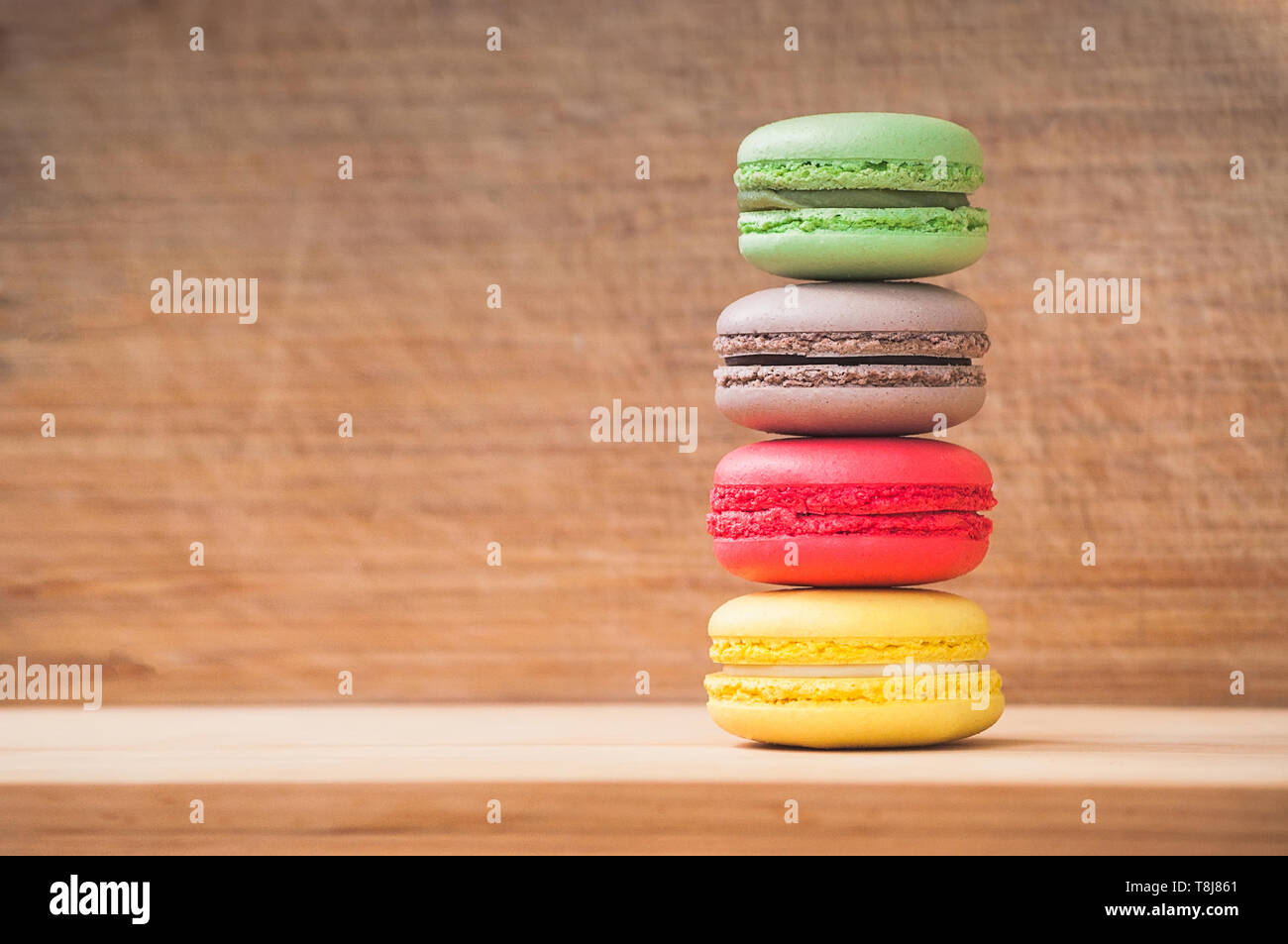 Quattro gustosi colorati macarons francese isolato su texture di legno Foto Stock