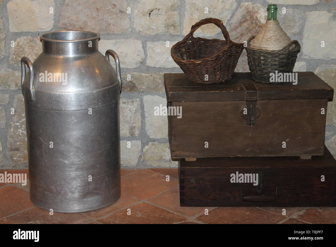 Strumenti rurali, cesto di vimini, bottiglia di vino e latte contenitore in acciaio Foto Stock