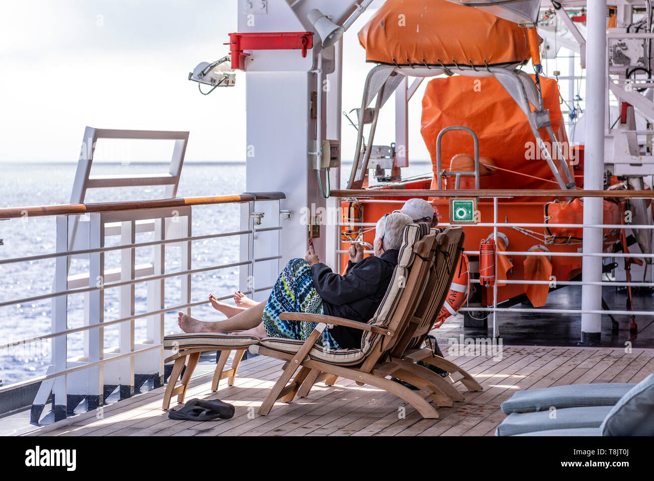 Due anziani rilassante sul ponte chaiirs sul Holland America nave da crociera; Eurodam. Foto Stock