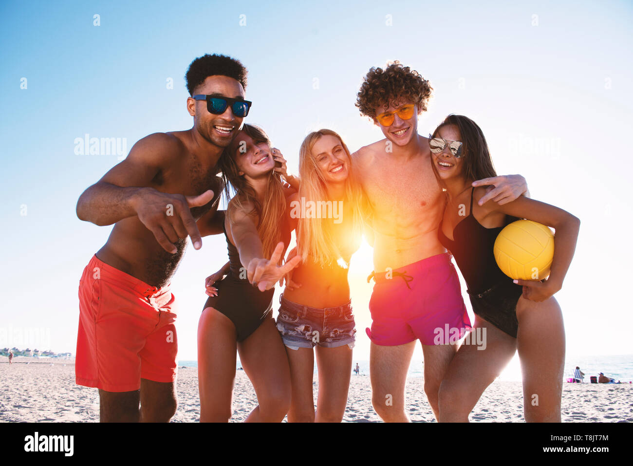 Gruppo di amici a giocare a beach volley in spiaggia. Mattina, alla luce del sole. Foto Stock