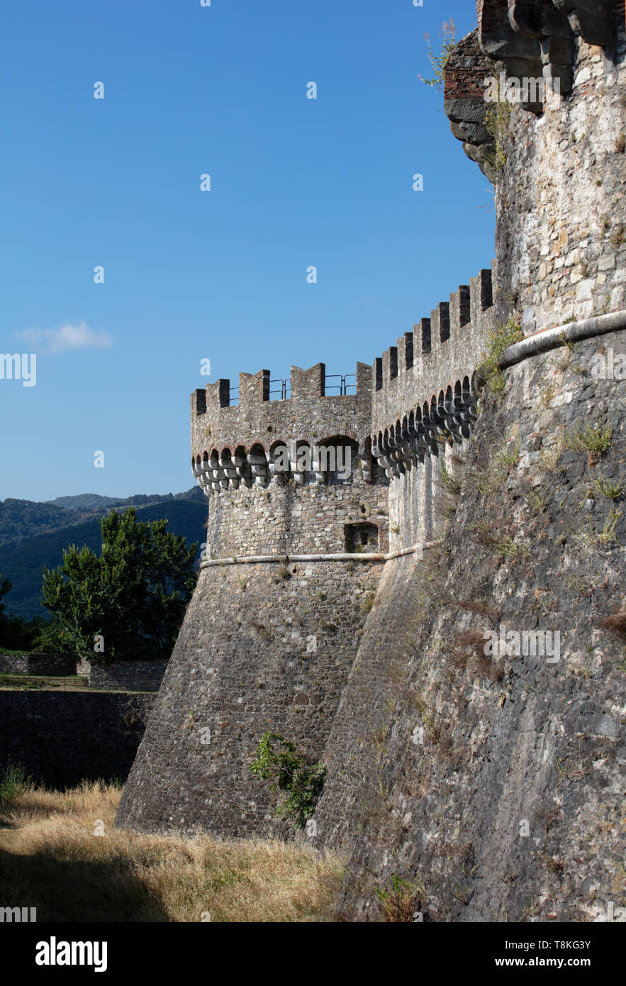 Il castello medievale di mura e torri che mostra le merlature contro un Cielo di estate blu a Sarzana, Liguria. Foto Stock