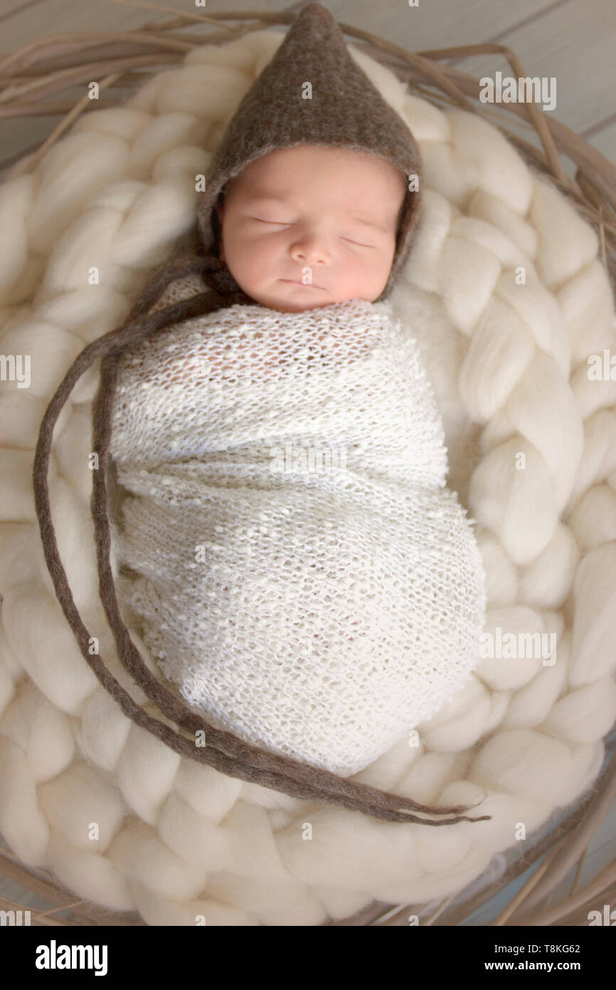 Neonato bambino addormentato indossando un cappello marrone Foto Stock