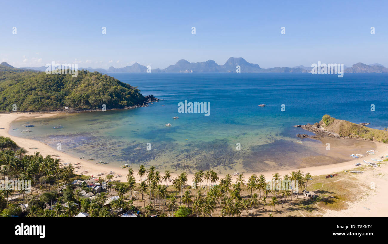 Piccola baia con una spiaggia di sabbia bianca, vista dall'alto. Insediamenti e la natura in isole filippine. Foto Stock