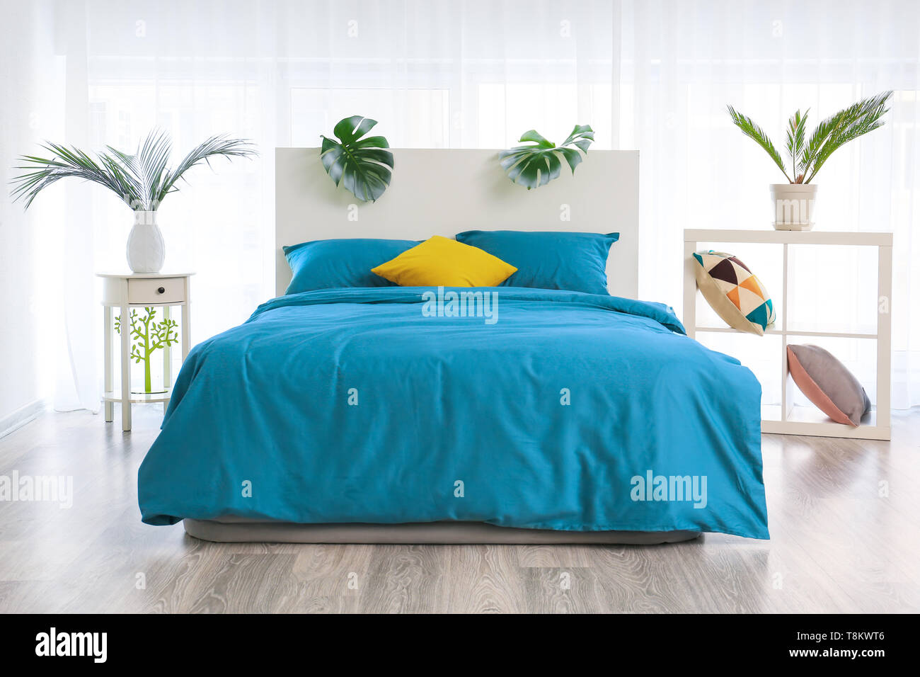 Interno del moderno e confortevole camera da letto con foglie tropicali Foto Stock