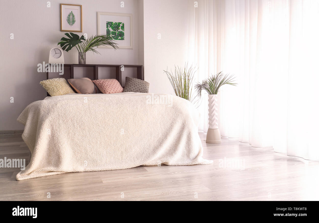 Interno del moderno e confortevole camera da letto con foglie tropicali Foto Stock