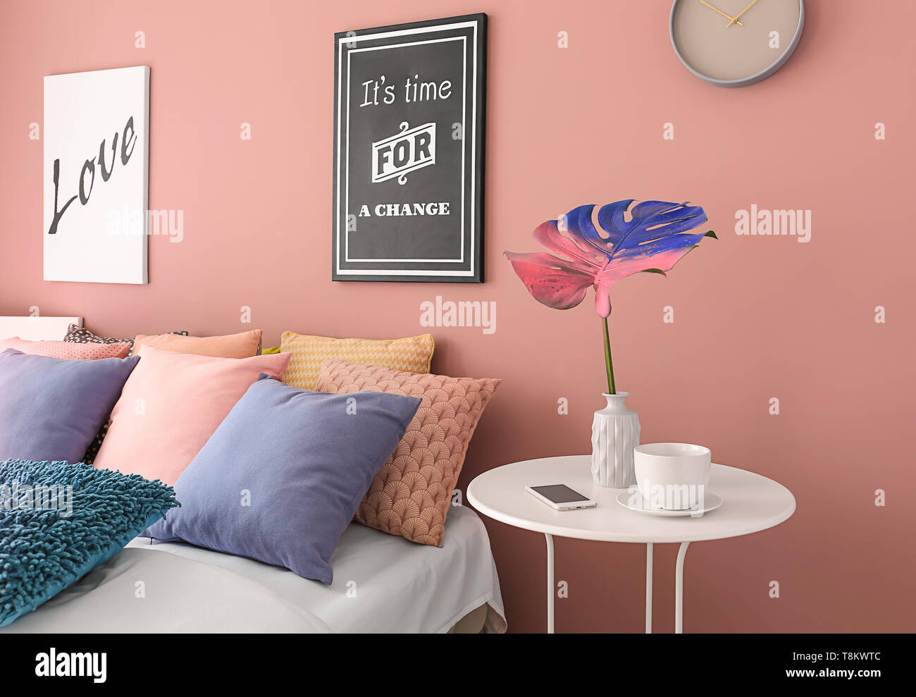 Interno del moderno e confortevole camera da letto con colori foglia di monstera in vaso sul tavolo Foto Stock