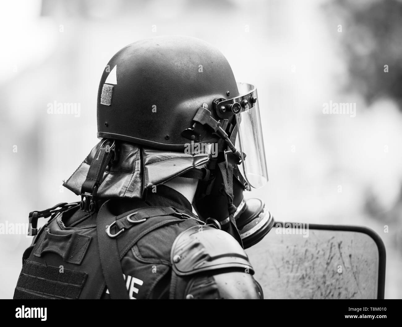 Immagine in bianco e nero del funzionario di polizia indossando maschera a gas contro i gas lacrimogeni a protestare con giacche gialle Gilets Jaunes Foto Stock