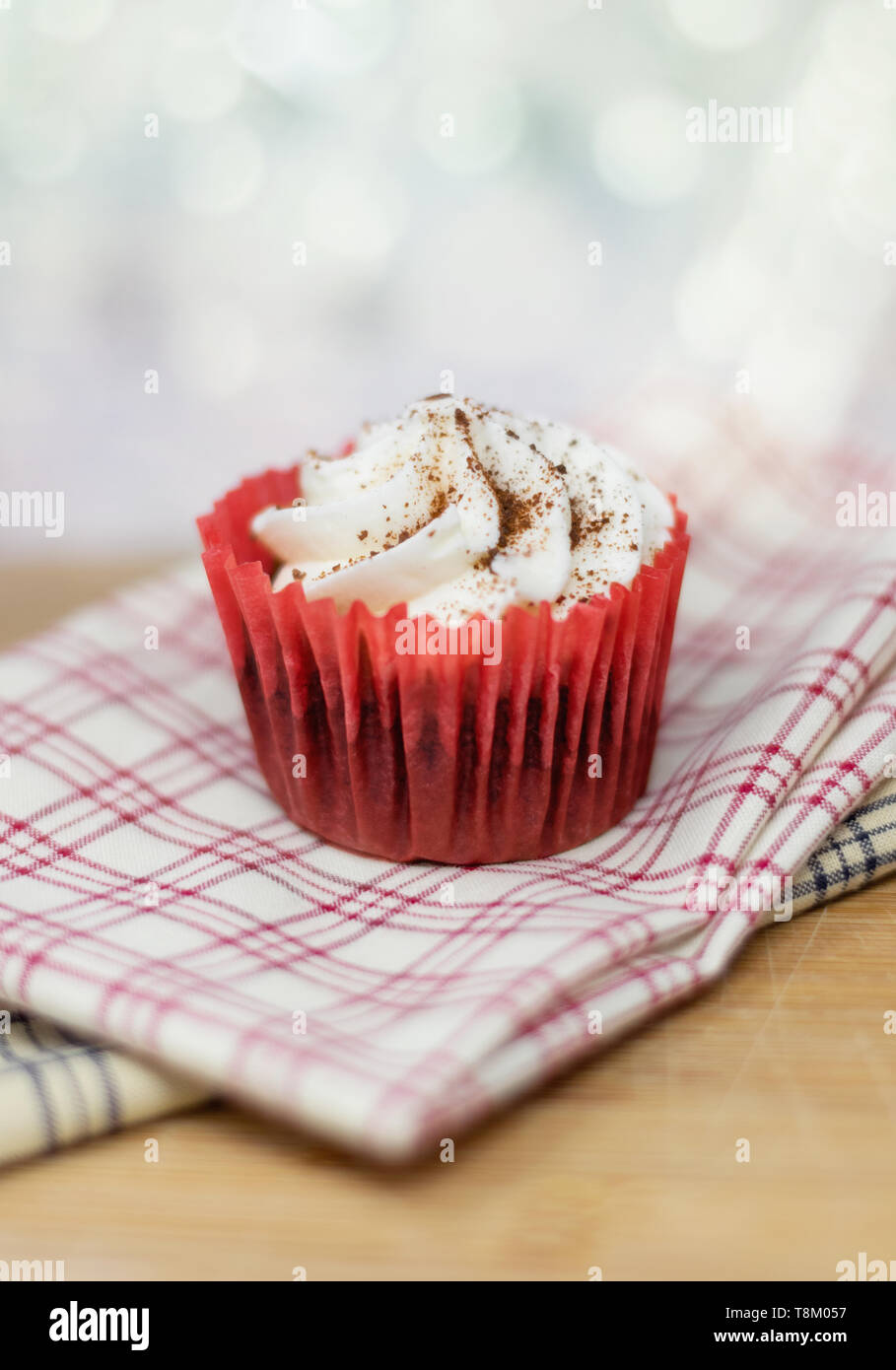 Red Velvet cupcake decorativo su plaid tessuto con una profondità di campo ridotta e un sfondo bokeh di fondo Foto Stock