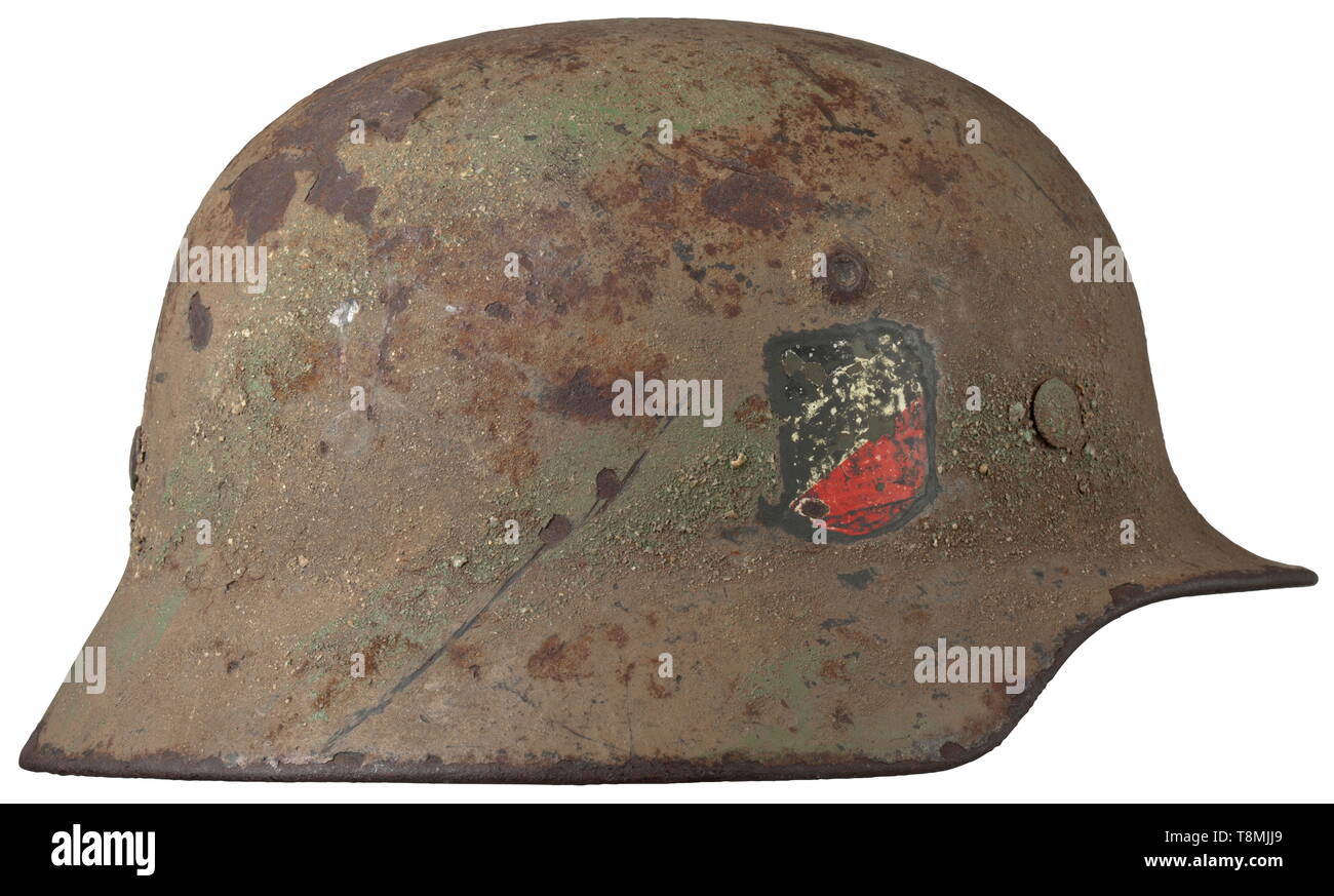 Un casco in acciaio M 40 con vernice di mimetizzazione e i resti delle decalcomanie cranio originariamente dipinta campo-grigio, lateralmente la timbratura ha colpito 'SE 62'. Verde chiaro/marrone ruvida vernice camouflage, le decalcomanie successivamente esposta. In intatta rusty " come trovato' condizione, il rivestimento essiccato fuori, con difetti. Il camuffamento tipico per la fase finale della guerra. storica, storica, esercito, eserciti, forze armate, militare, militaria, xx secolo, Editorial-Use-solo Foto Stock