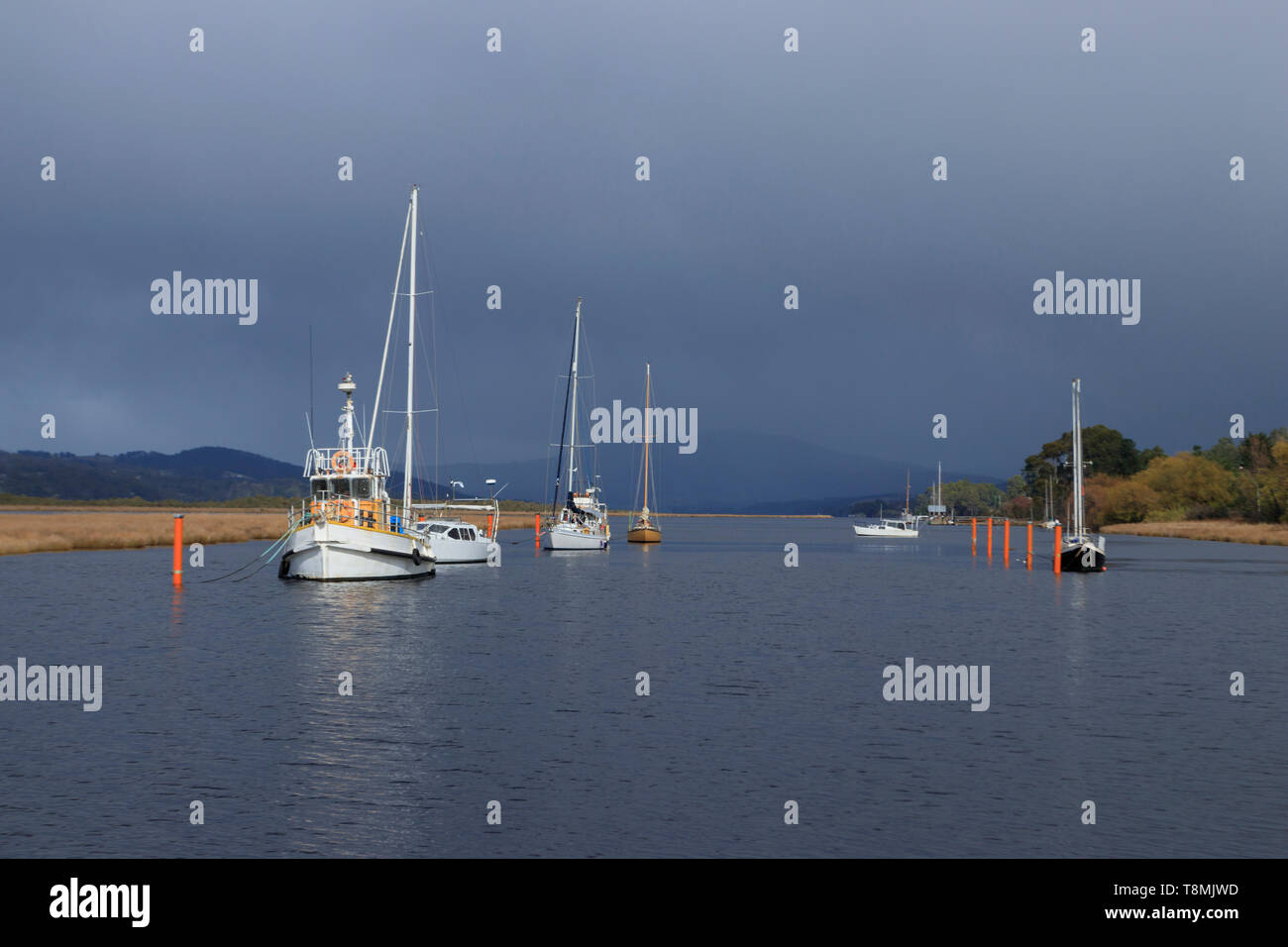 Barche ormeggiate presso Franklin sul Fiume Huon in Sud Tasmania, Australia con scuri pioggia nuvole in background. Foto Stock