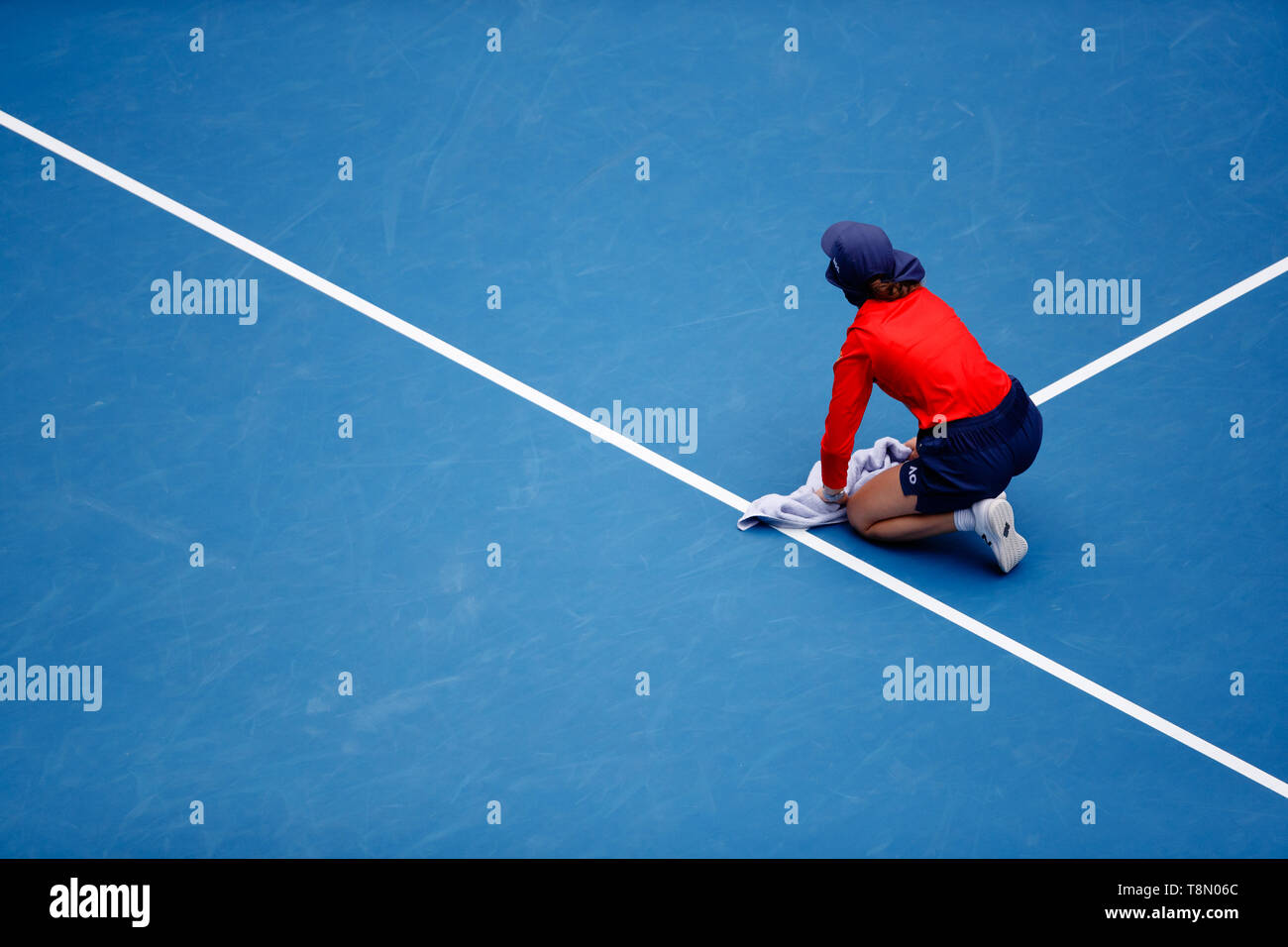 Una sfera kid wipes giù la Rod Laver Arena con un asciugamano dopo piove. Foto Stock