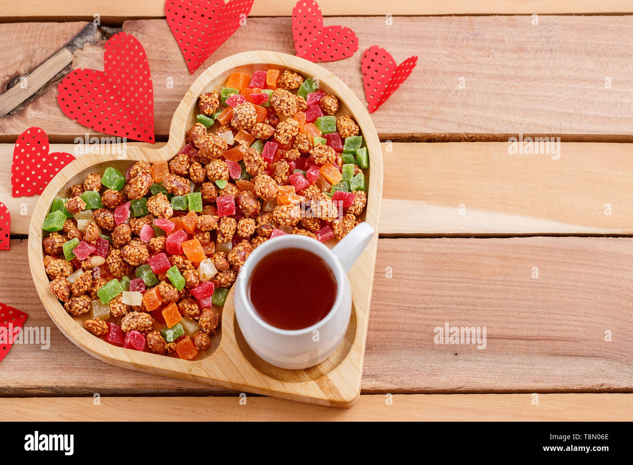 Colorata frutta secca in un vassoio a forma di cuore con tè Foto Stock