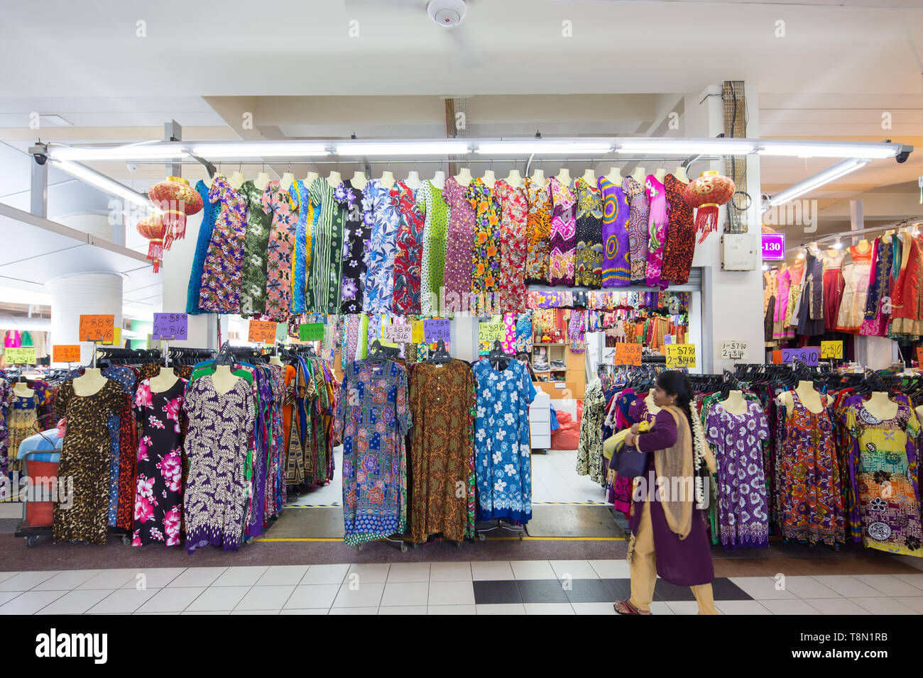 Una donna indiana in sari viola che cammina di fronte a un negozio di sari al Tekka Market, Singapore, nel sud-est asiatico. Foto Stock