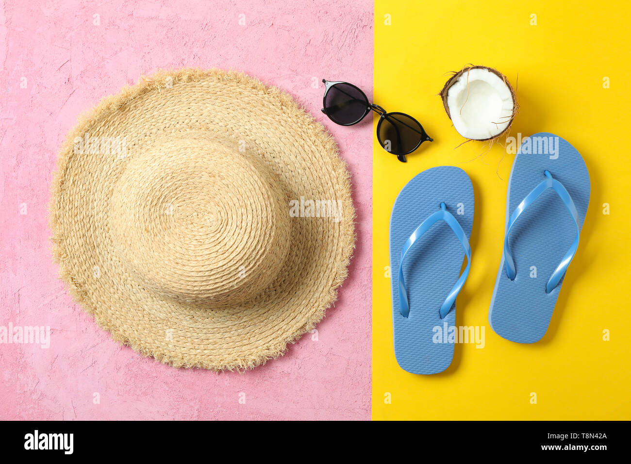 Cappello di paglia, flip-flop, occhiali da sole e noce di cocco in due tonalità di sfondo, spazio per il testo e la vista dall'alto. La vacanza estiva sfondo Foto Stock