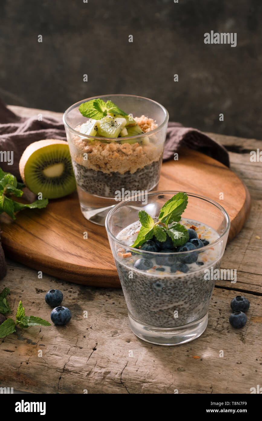 Una sana prima colazione - ciotola di muesli, bacche e frutta, kiwi, latte Foto Stock