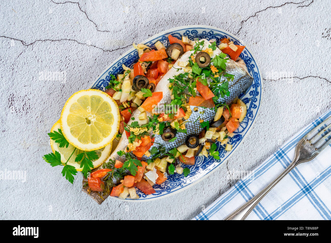 Mare Mediterraneo bass farcite con i pomodori, i limoni, il finocchio e le olive - vista dall'alto. La cucina greca. Foto Stock