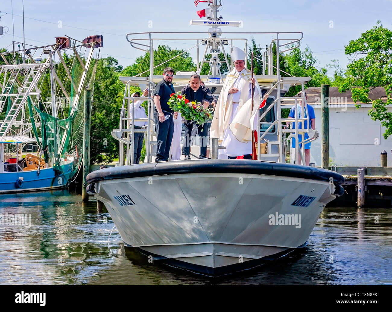 Il parroco di Santa Margherita la Chiesa cattolica lancia una corona di fiori in acqua durante la benedizione della flotta in Bayou La Batre, Alabama. Foto Stock