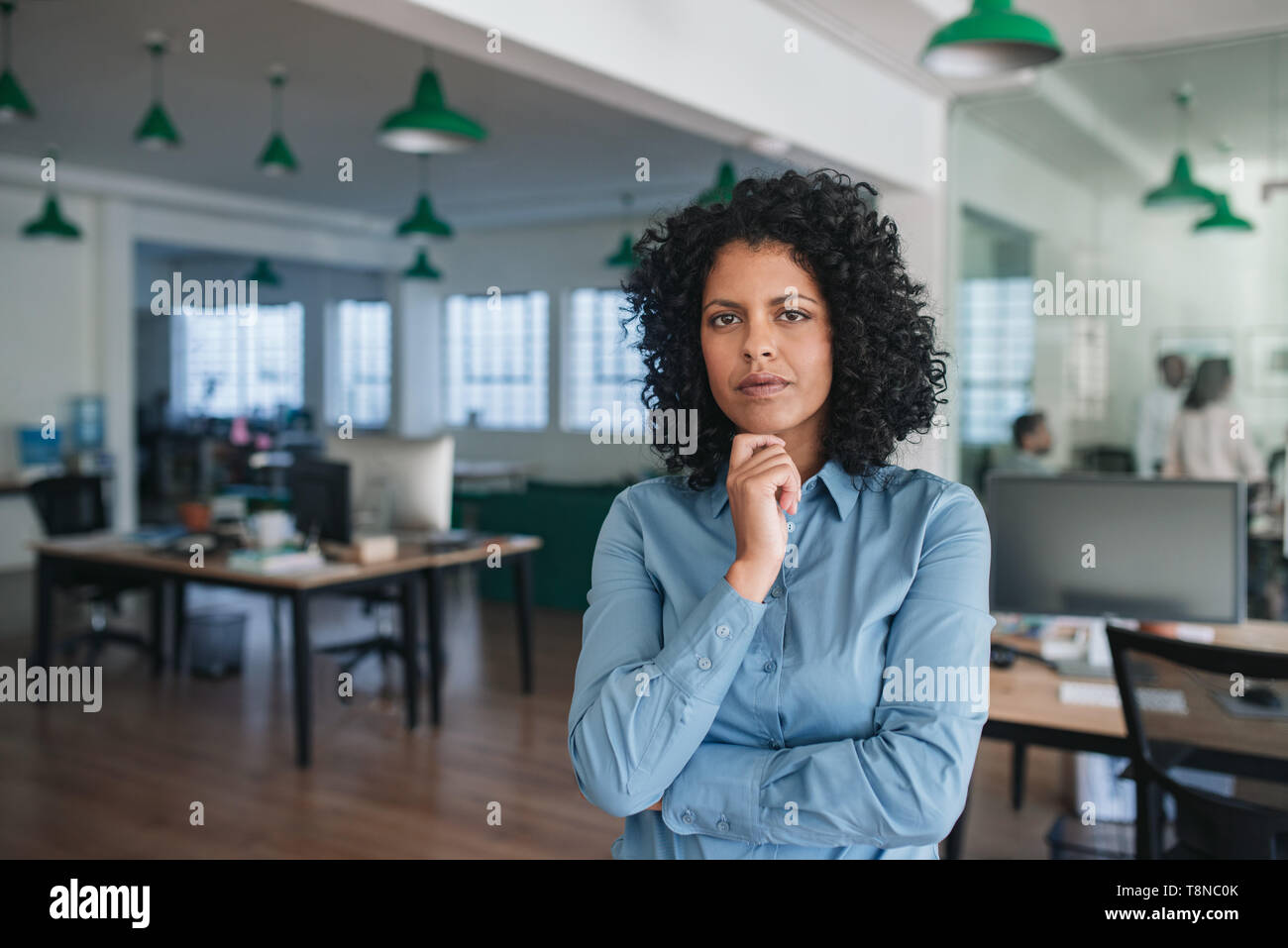 Giovane imprenditrice in piedi con fiducia in un ufficio moderno Foto Stock