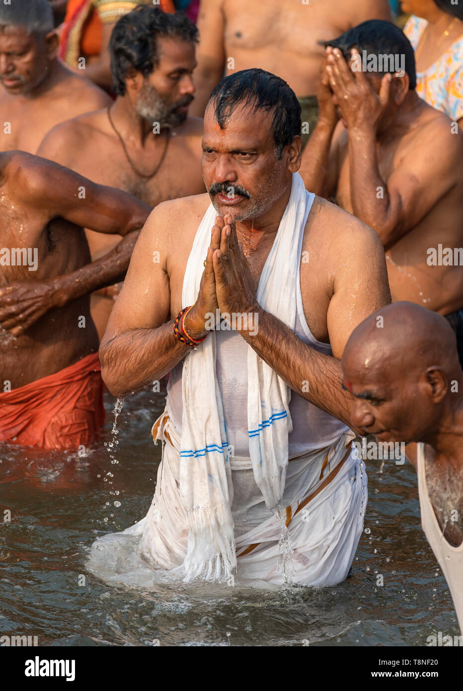 Uomo compie il rituale puja preghiera nel fiume Gange, Varanasi, India Foto Stock