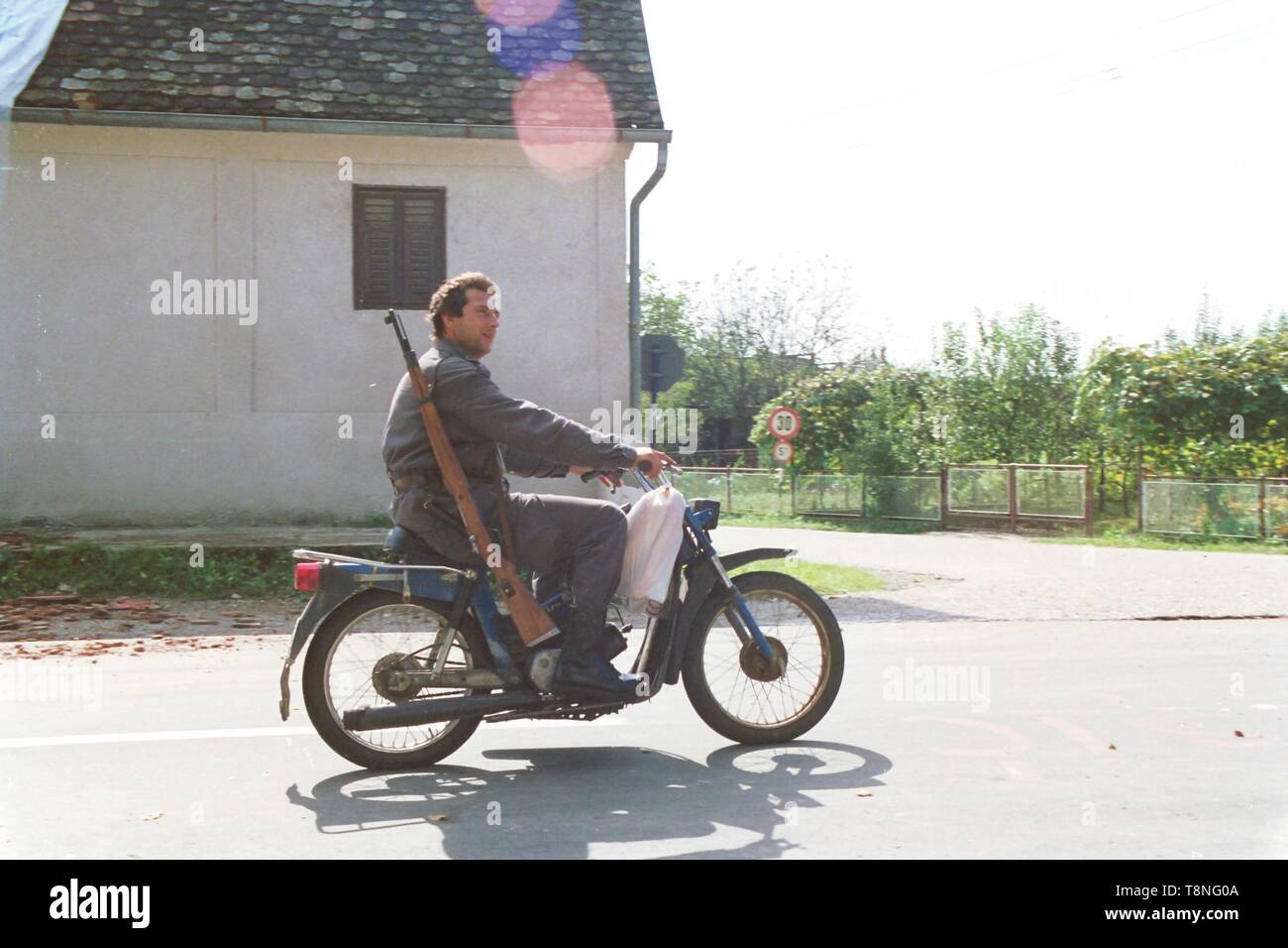 Un poliziotto croato, armati per la guerra i capi su un motociclo per il front-line nel villaggio di Moscenica durante la disgregazione della Jugoslavia nel 1991-1992. Foto di Adam Alexander Foto Stock