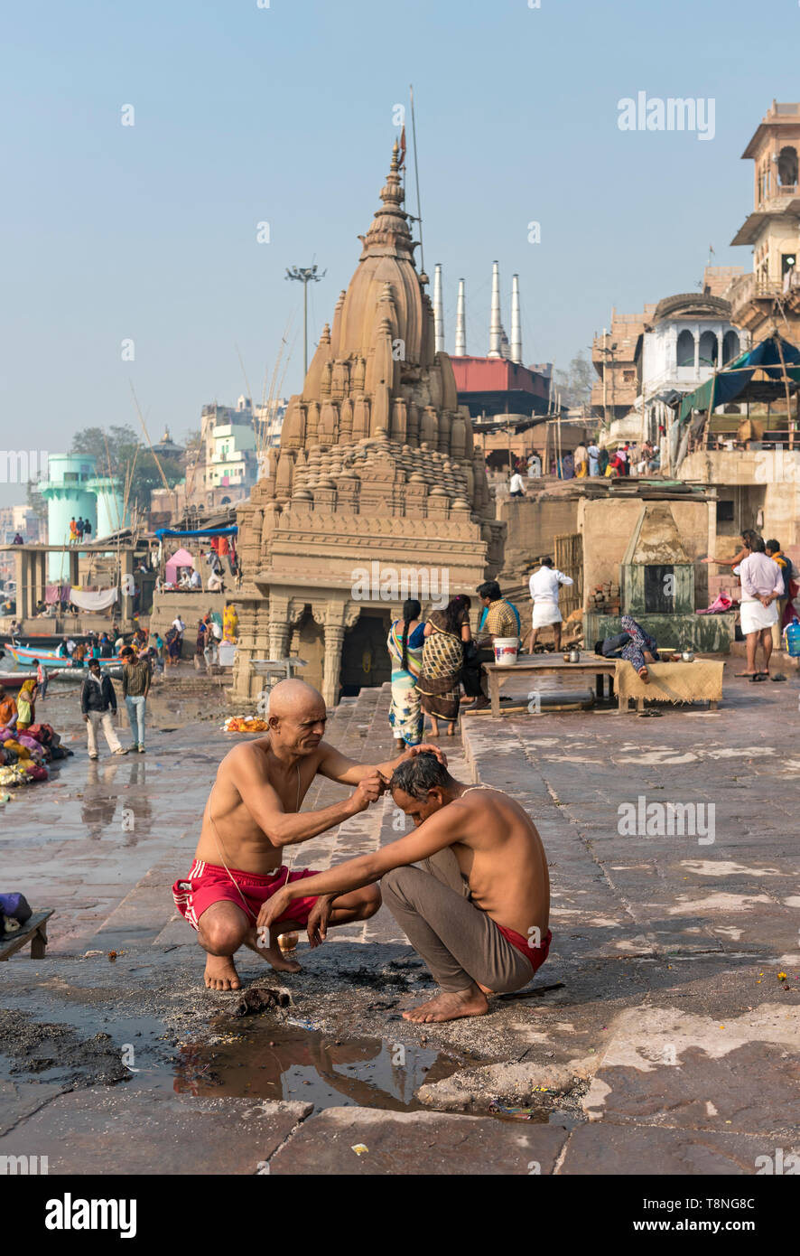 L'uomo diventa la sua testa rasata in parte anteriore del pendente Mahadev Ratneshwar tempio da gange Varanasi, India Foto Stock