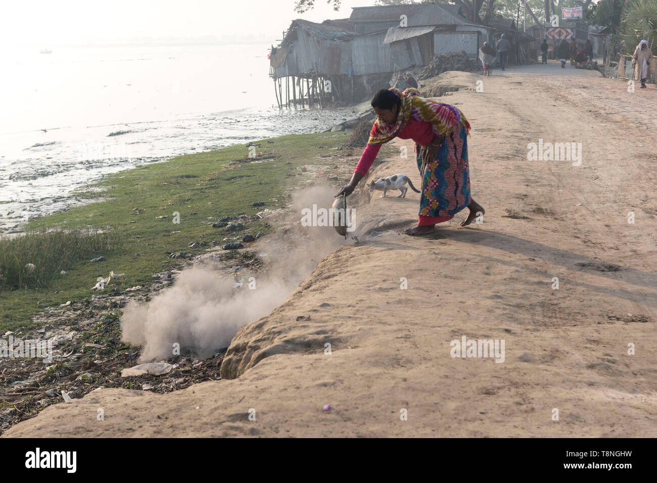 Una donna pulisce la sua cenere di cucina quotidiana nel fiume. Foto Stock